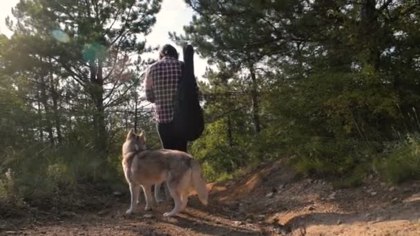 man with guitar walking with two siberian husky dog in forest - Video, Çekim