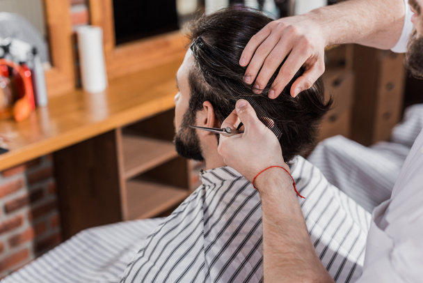 Bärtiger Mann lässt sich im Friseurladen die Haare schneiden - Foto, Bild