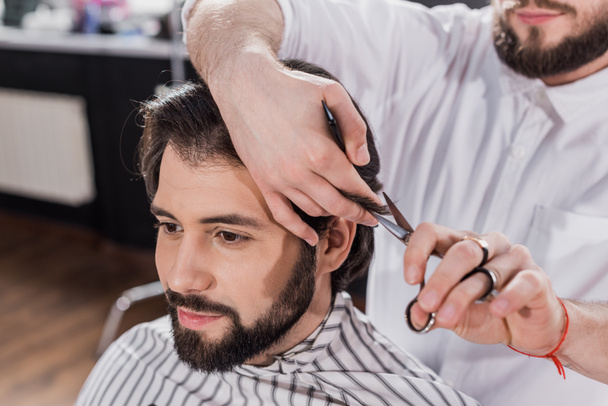 smiling bearded man getting haircut in barbershop - Zdjęcie, obraz