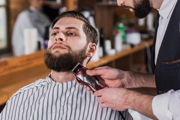крупным планом парикмахера, бреющегося с машиной для стрижки волос
 - Фото, изображение