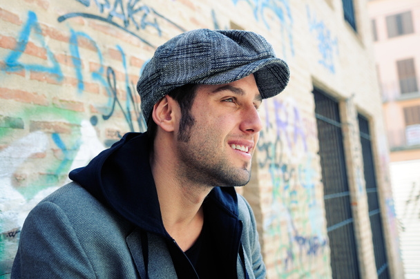 Portrait of handsome man in urban background wearing a retro cap - Photo, Image