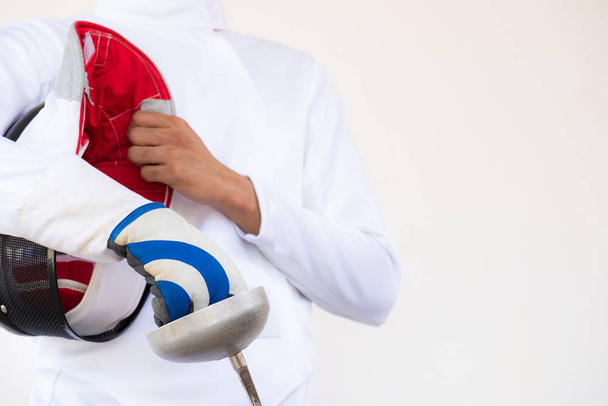 Close-up of a fencer in white fencing suit and holding his mask  - Photo, Image