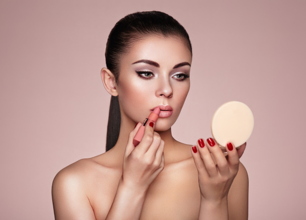 Beautiful woman paints lips with lipstick - Foto, imagen