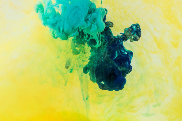 background with green and turquoise paint flowing in yellow water - Foto, Bild