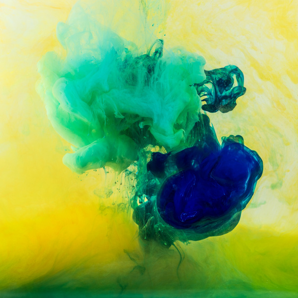 remolinos abstractos de pintura verde y azul que fluyen en agua amarilla
 - Foto, Imagen