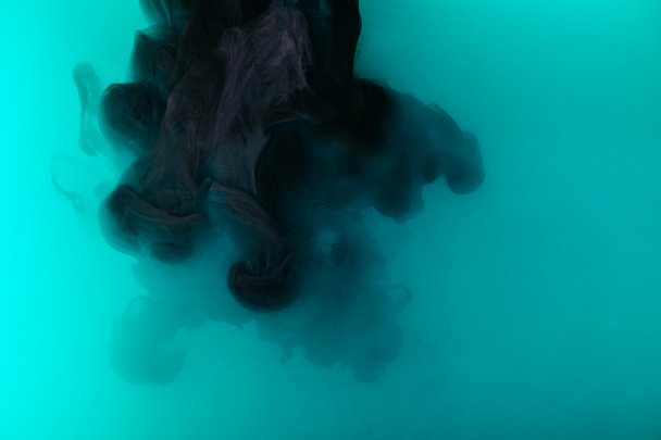 abstract artistic background with black paint in turquoise water - Photo, Image