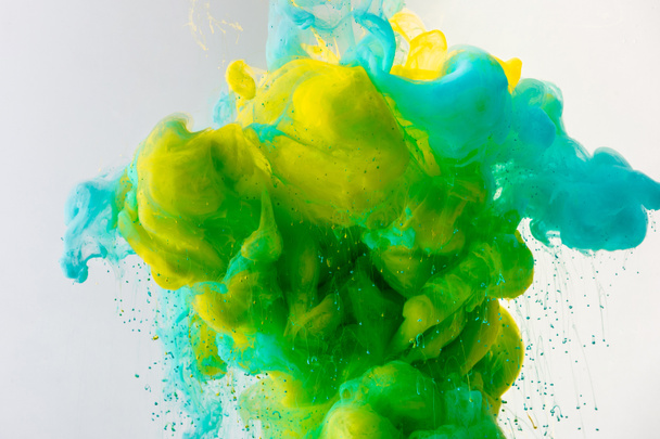 artistic background with flowing turquoise, yellow and green paint in water, isolated on grey - Foto, Imagem