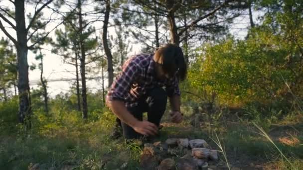 hiker man building place for campfire in forest - Materiaali, video