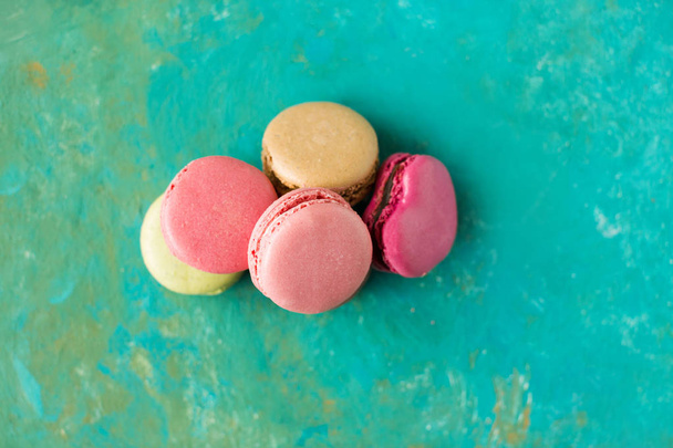 stack of colored macaroons on green background, top view - Foto, imagen