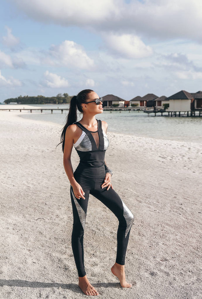 fashion photo of beautiful woman with dark hair in sport suit relaxing on Maldive islands - Foto, imagen