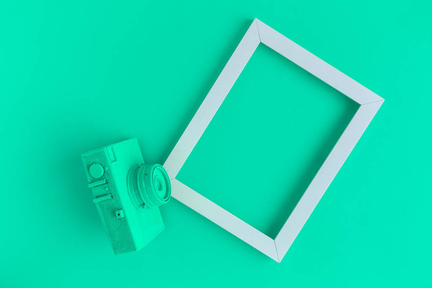 Flat lay of turquoise vintage camera and photo frame background - Fotó, kép