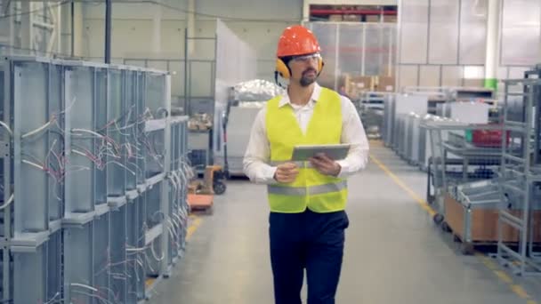 Un travailleur avec tablette marche dans une installation, plancher de production industrielle, entrepôt
. - Séquence, vidéo