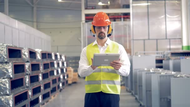 Un hombre trabaja en una instalación industrial, comprobando la información en su tableta
. - Imágenes, Vídeo