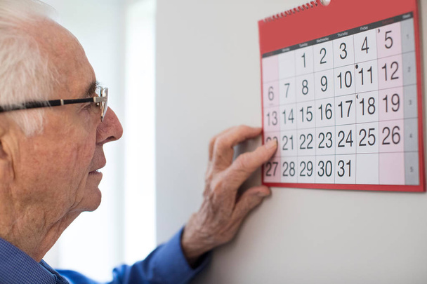 Confused Senior Man With Dementia Looking At Wall Calendar - Φωτογραφία, εικόνα