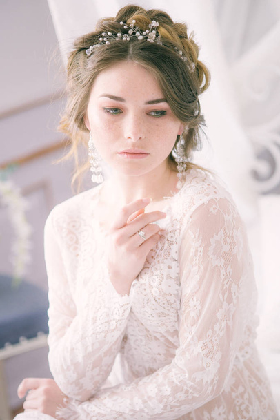 Portrait of beautiful bride. Morning of the bride. Wedding morning. Makeup. Bride with cones and fair hair. Fragile bride in white lace negligee - Foto, Imagem
