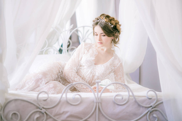 Portrait of beautiful bride. Morning of the bride. Wedding morning. Makeup. Bride with cones and fair hair. Fragile bride in white lace negligee - Foto, immagini