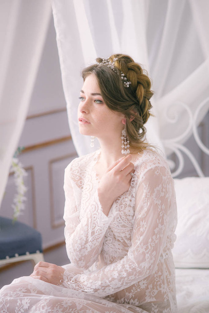 Portrait of beautiful bride. Morning of the bride. Wedding morning. Makeup. Bride with cones and fair hair. Fragile bride in white lace negligee - Fotoğraf, Görsel