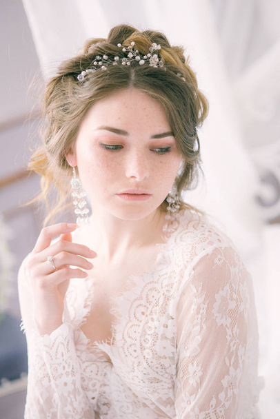Portrait of beautiful bride. Morning of the bride. Wedding morning. Makeup. Bride with cones and fair hair. Fragile bride in white lace negligee - Photo, image