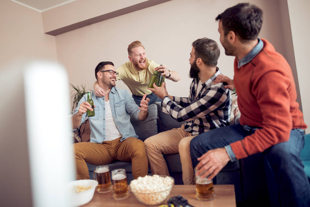 Φιλία, τεχνολογία, παιχνίδια και αρχική έννοια-χαμογελώντας αρσενικούς φίλους πίνουν μπύρα στο σπίτι. - Φωτογραφία, εικόνα
