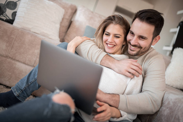 Jovem casal sentado na sala de estar e usando laptop
. - Foto, Imagem