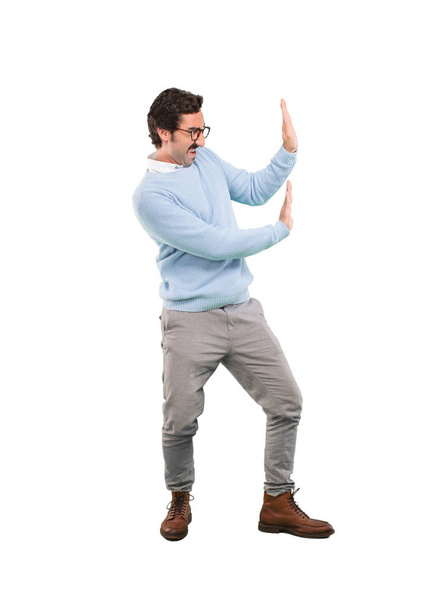 Young crazy man pushing or holding sign. Full body cutout person against white background. - 写真・画像