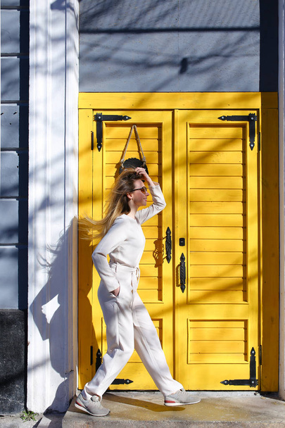 Young fashionable girl standing near cafe door in sun rays. - Φωτογραφία, εικόνα