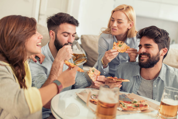 Vrienden plezier thuis, pizza eten en drinken wat koud bier. - Foto, afbeelding