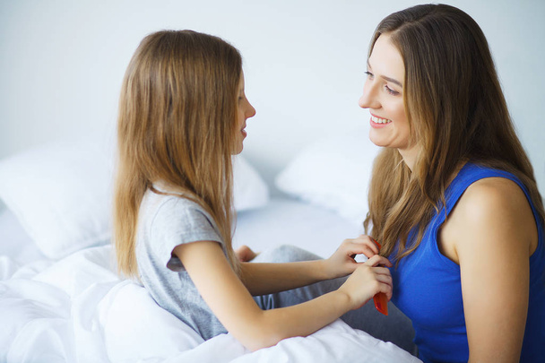 Woman and young girl lying in bed smiling - Photo, Image