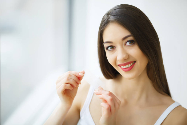 Sbiancamento dei denti. Bella donna sorridente tenendo striscia sbiancante
 - Foto, immagini
