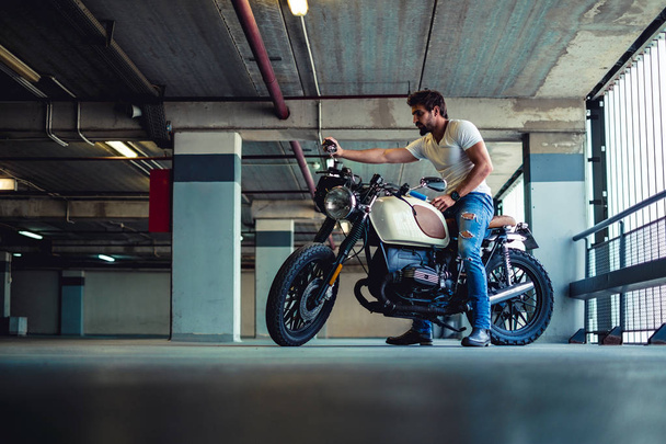 Maço erkek bir garaj doğru motosiklet aynaya bakarak - Fotoğraf, Görsel