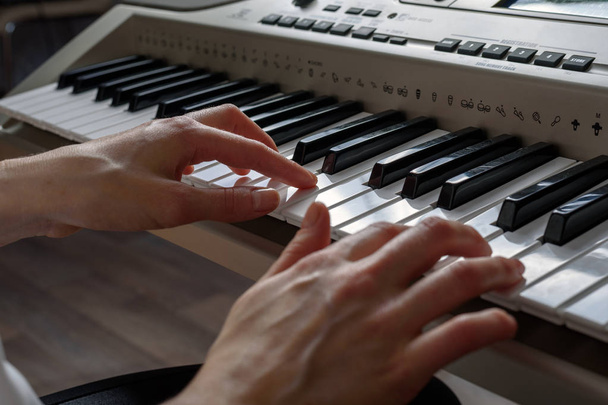 Vue latérale des mains féminines jouant du synthétiseur, composant de la musique
 - Photo, image