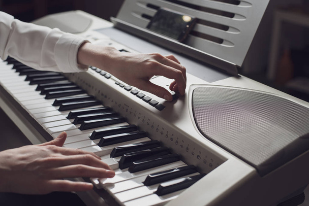 Imagen tonificada de las manos femeninas primer plano del sintetizador de melodía
 - Foto, imagen