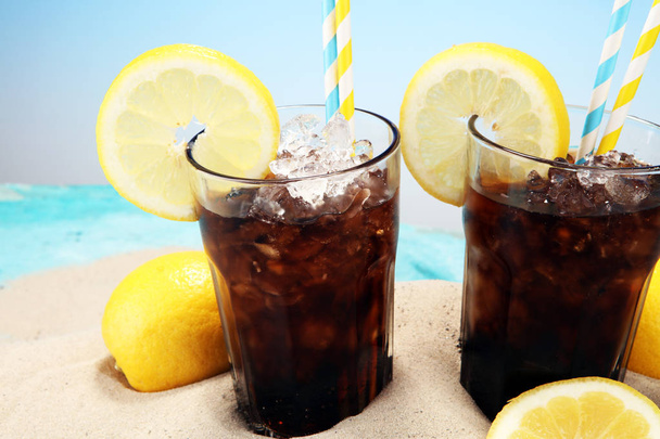 Softdrink with ice cubes, lemon and straw in glass. - Photo, Image