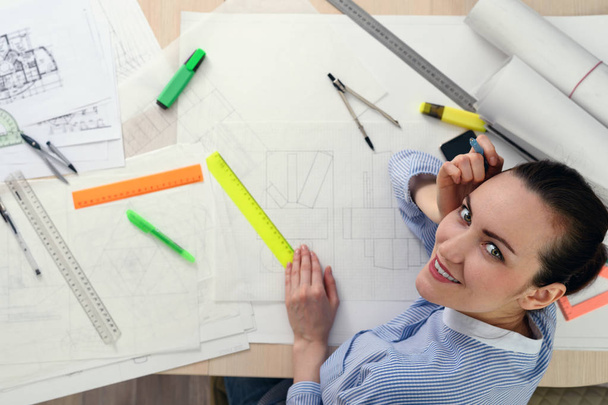 Portrait of smiling female architect on the table with drawings, rulers, pencils, compasses - Фото, зображення
