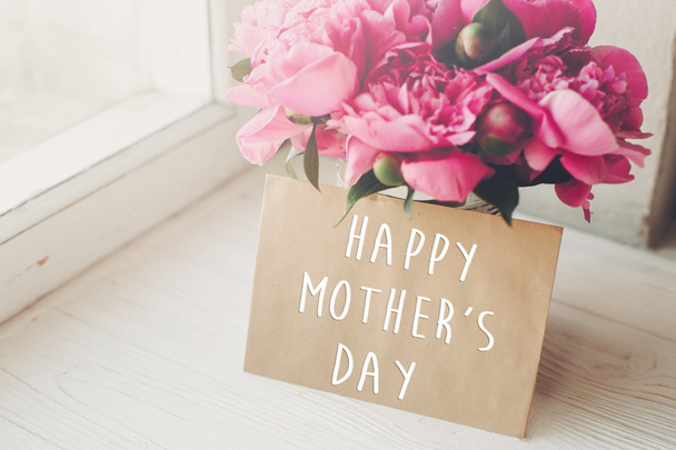 κείμενο ημέρα ευτυχισμένη μητέρα του σκάφους κάρτα και ανθοδέσμη ροζ παιώνιες ρουστίκ λευκό ξύλινο παράθυρο στο φως. έννοια floral ευχετήρια κάρτα. ημέρα της μητέρας. μαλακό προσφορά άνοιξη εικόνας - Φωτογραφία, εικόνα
