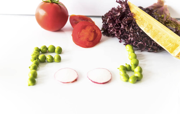Food writing with green peas and red radish on the isolated background with knife - Foto, afbeelding