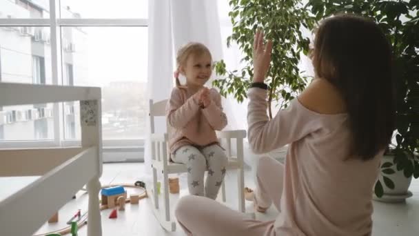 Little girl sitting in rocking chair and play with mother - Metraje, vídeo