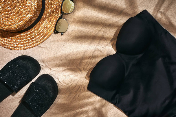 Sandaali, olkihattu ja aurinkolasit hiekkapohjalla, ylhäältä katsottuna
 - Valokuva, kuva