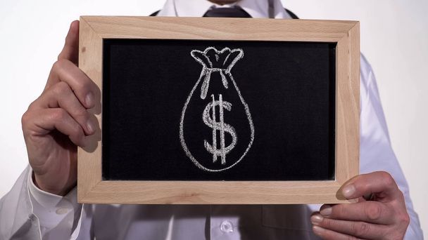 saco de dólar dibujado en pizarra en manos del médico, medicina costosa, soborno
 - Foto, imagen