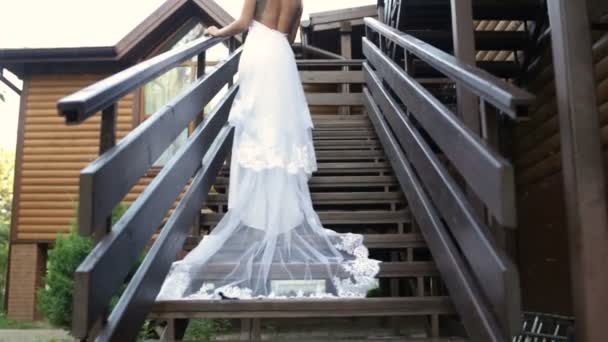 Όμορφη νύφη με μακρύ πέπλο κάτω από τις σκάλες - Πλάνα, βίντεο