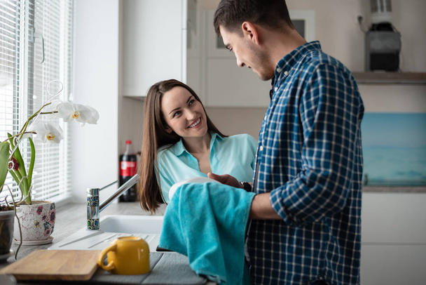 Couple washing dishes together after dinner, a happy family life - Photo, Image