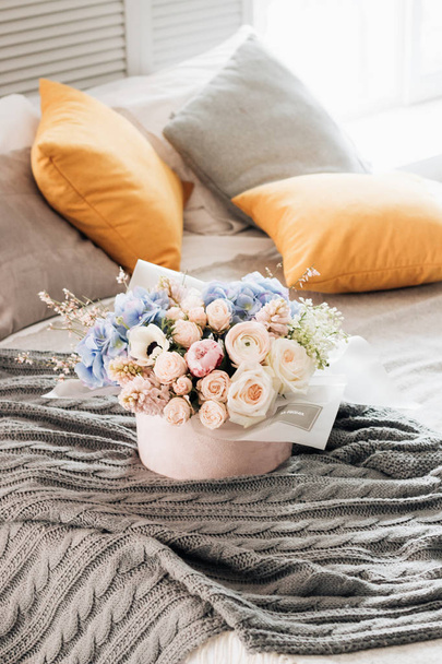 beautiful spring bouquet with tender pink ranunculus flowers and blue hydrangea in box on bed, elegant floral decoration  - Photo, Image