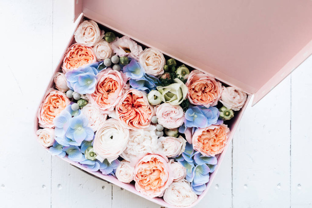 hermoso ramo de primavera con tiernas flores de ranúnculo rosa y hortensias azules en caja, elegante decoración floral
  - Foto, imagen