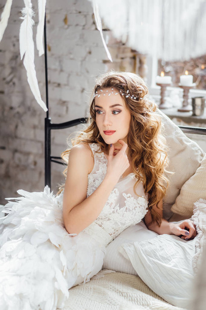 young beautiful woman posing in white dress with feathers  - Photo, image