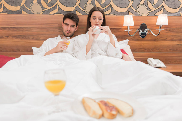 Attractive young couple in white robes, enjoying food and drink  - Fotoğraf, Görsel