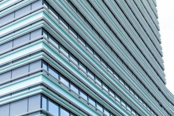 Ένα μεγάλο γυάλινο κτίριο με μια αντανάκλαση από το γαλάζιο του ουρανού. Αφηρημένο μπλε φόντο. Κτιρίου γραφείων στην μια ηλιόλουστη ημέρα. - Φωτογραφία, εικόνα