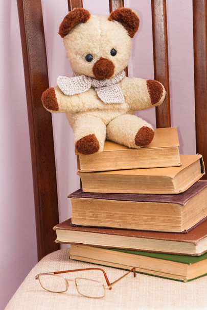 Vieux ours en peluche assis sur une pile de livres
 - Photo, image