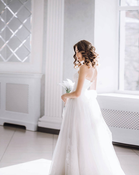 Beautiful bride with a bouquet in a white hall - Foto, afbeelding