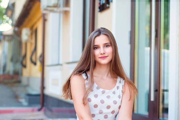 Teen girl with long brunette hair smiling sitting on steps. - Foto, Imagen
