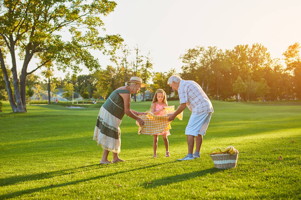 Meisje met grootouders, picknick. - Foto, afbeelding